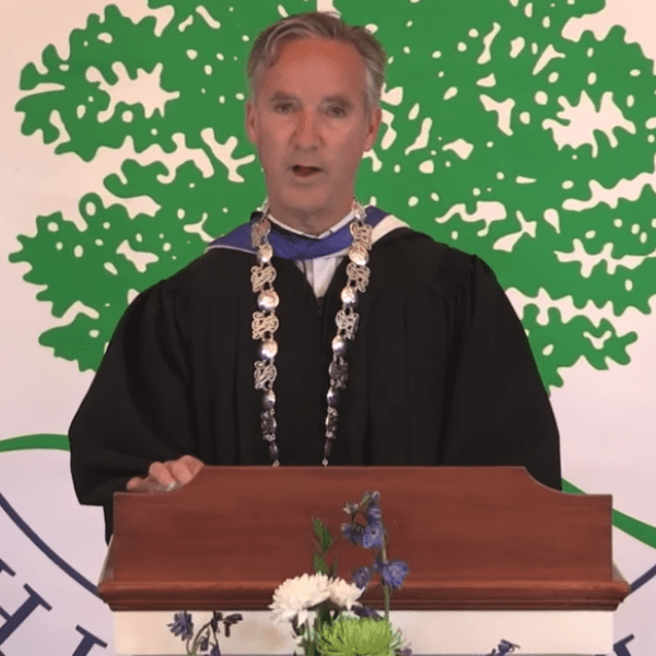man in robes at podium at graduation