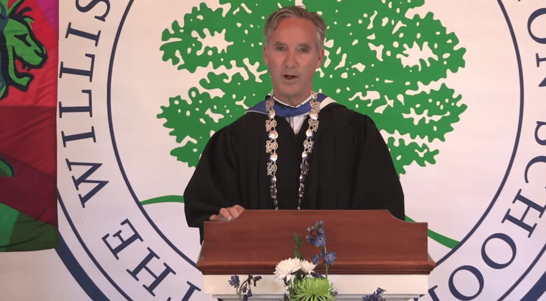 man in robes at podium at graduation