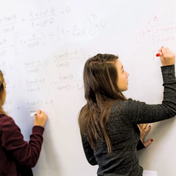 Girls at math whiteboard in class