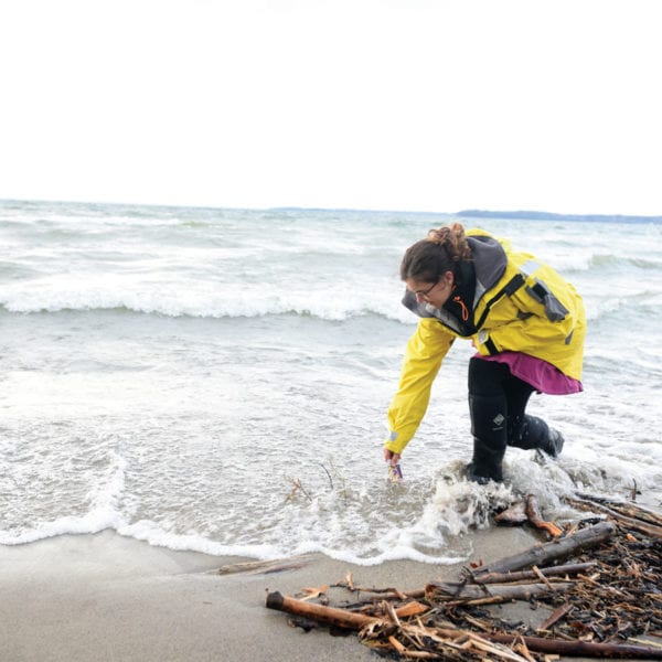 Alumni Rachel Miller standing in the ocean picking up trash