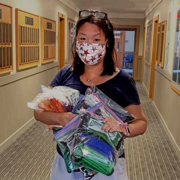woman in a mask holding bags of masks in hallway