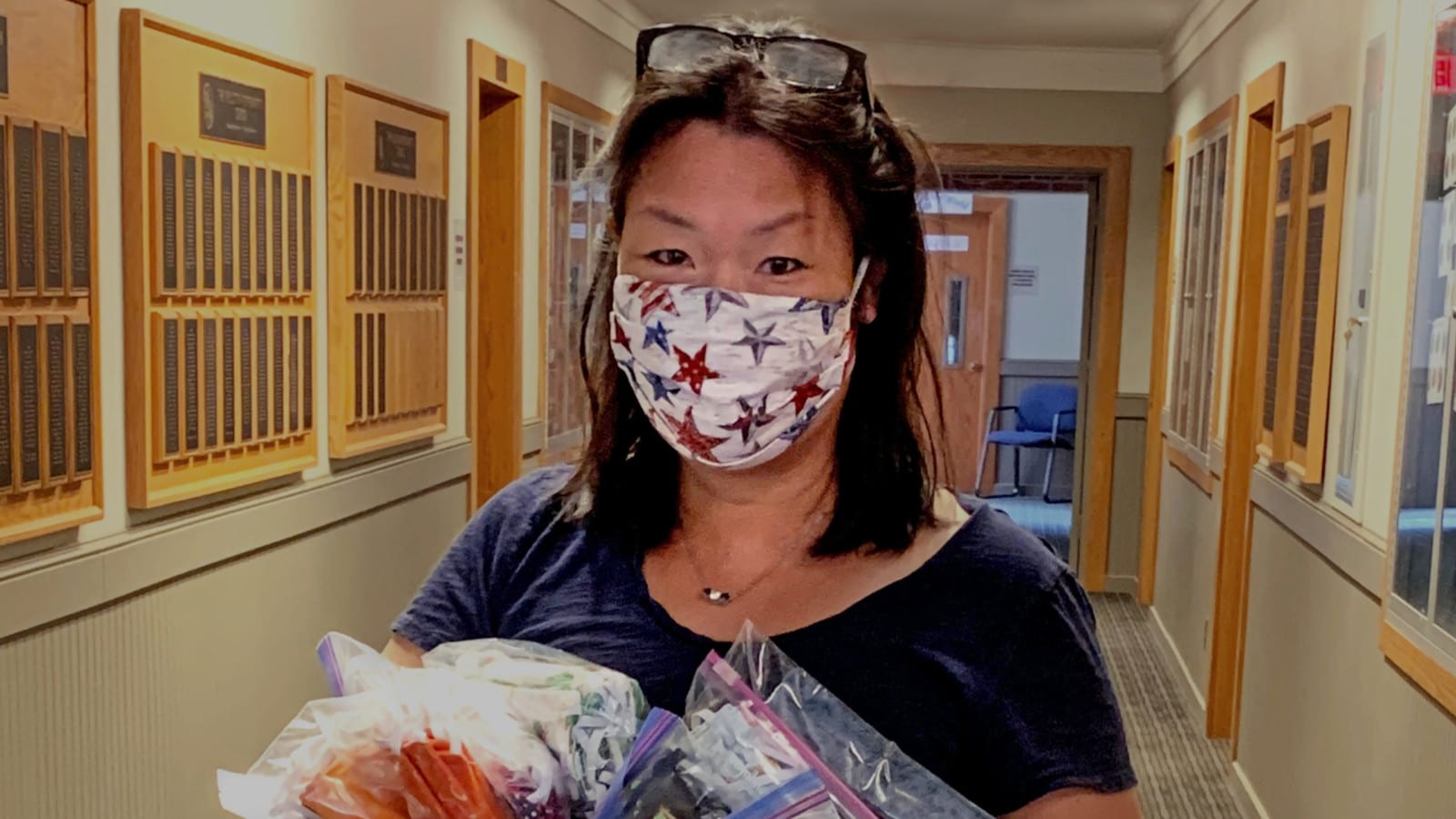 woman in a mask holding bags of masks in hallway