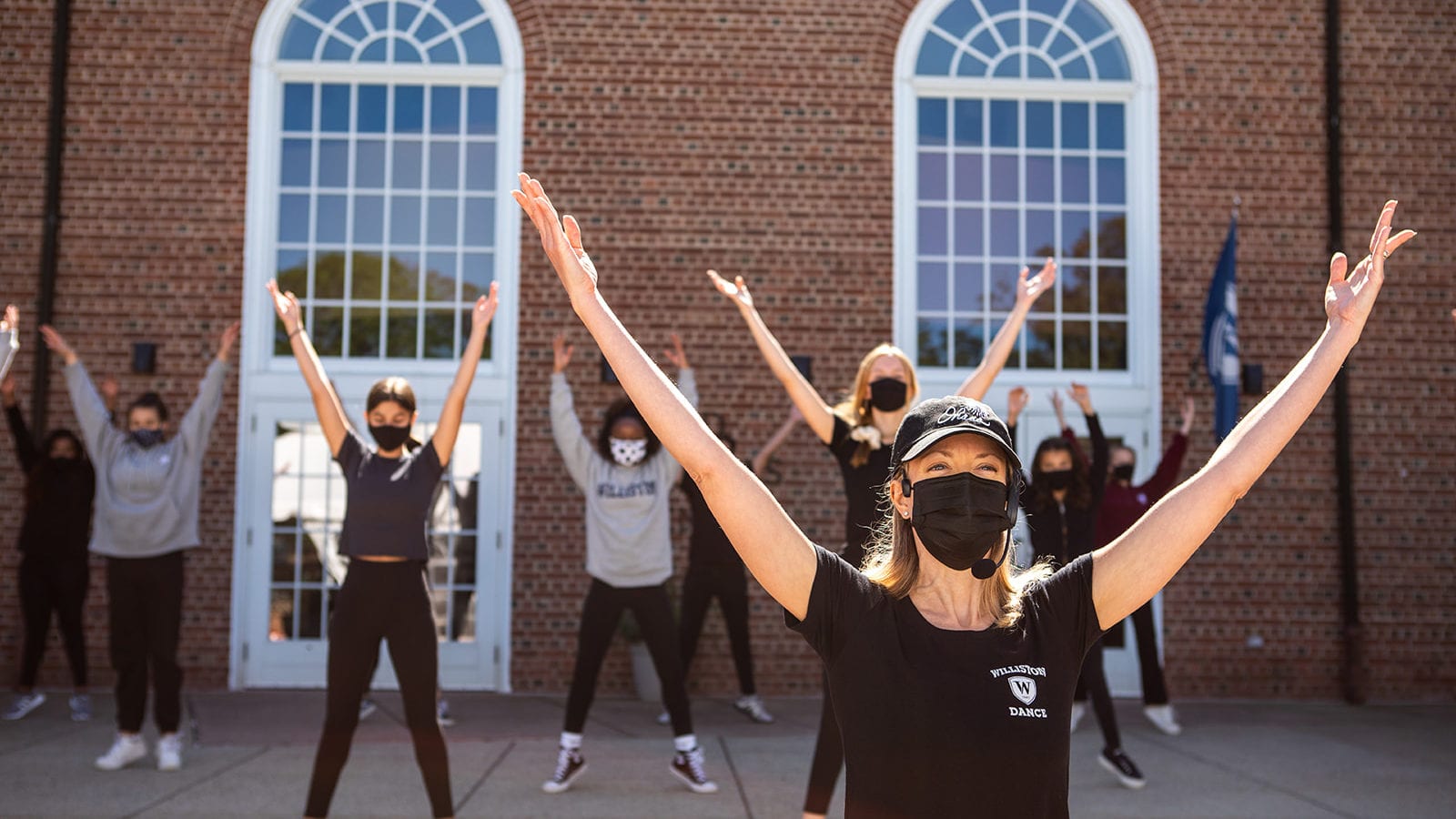 dancers in masks arms stretched up