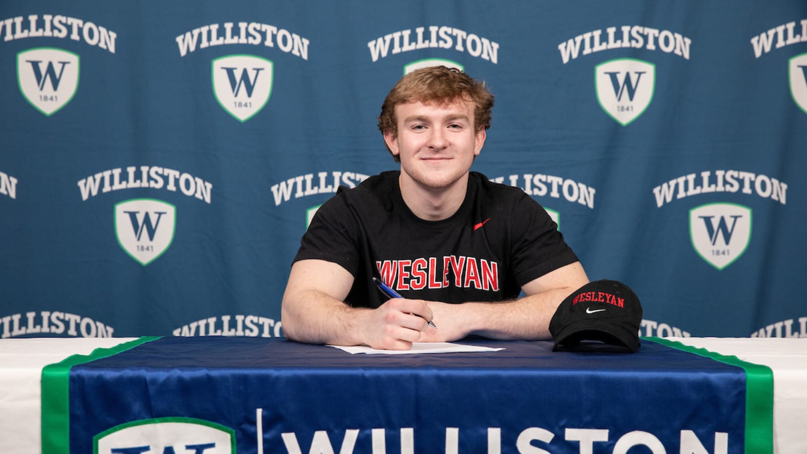 male student sitting at table with Williston northampton school logo