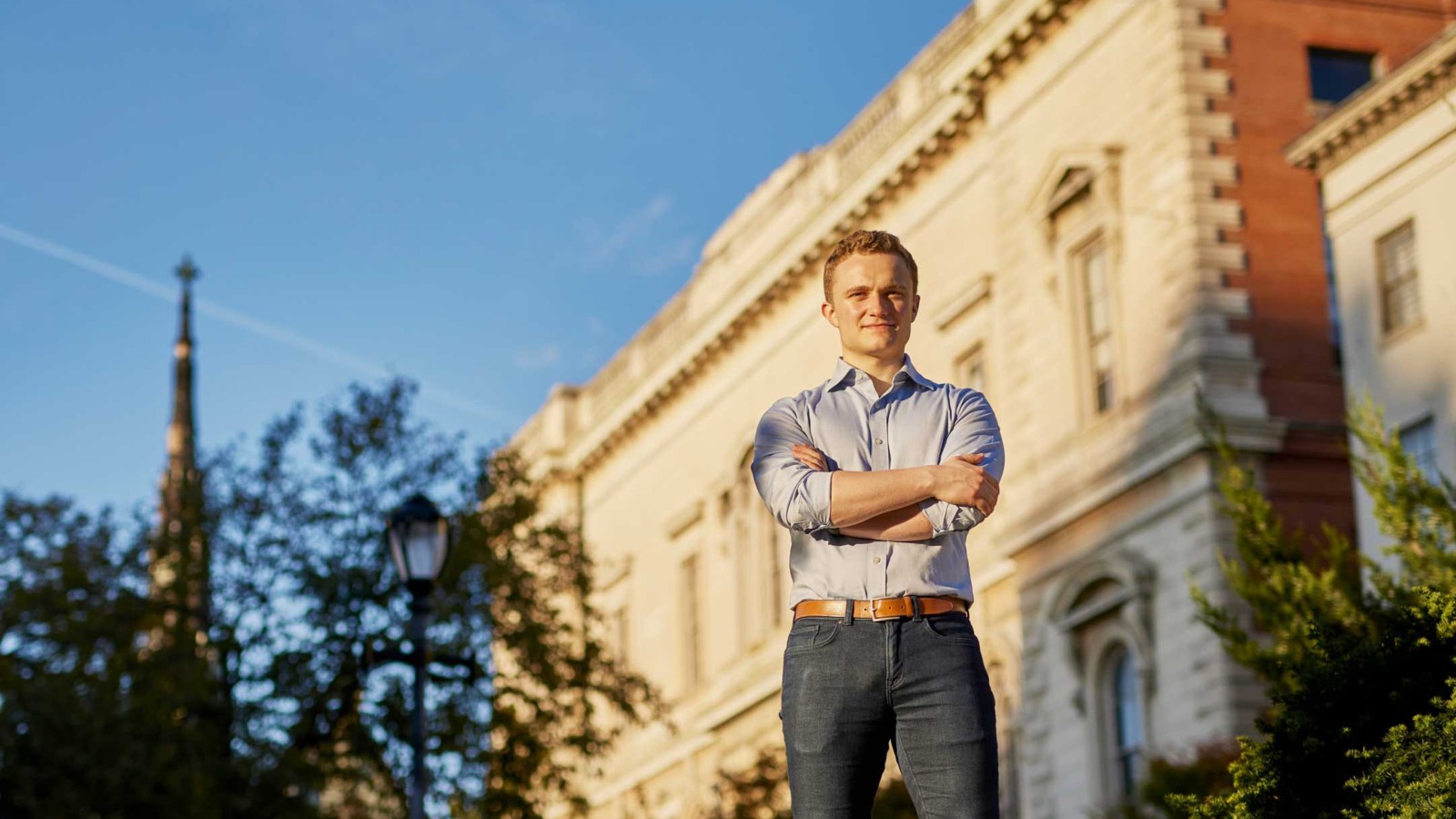 man with folded arms in front of a building