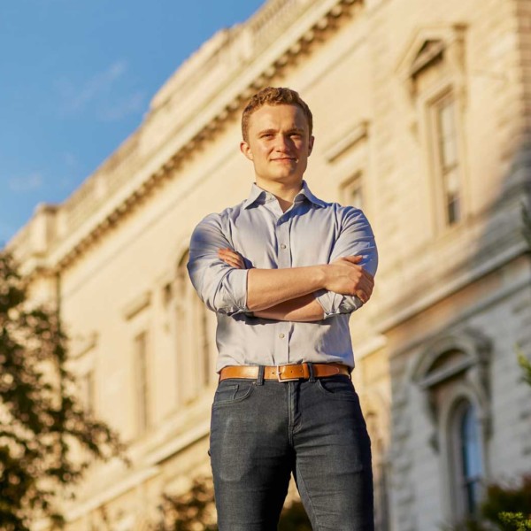 man with folded arms in front of a building