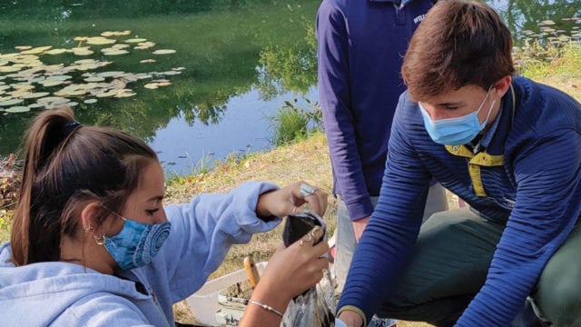 students wearing masks conducting outdoor science experiments