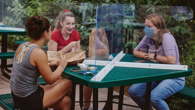 girls sitting at a table separated by plexiglass