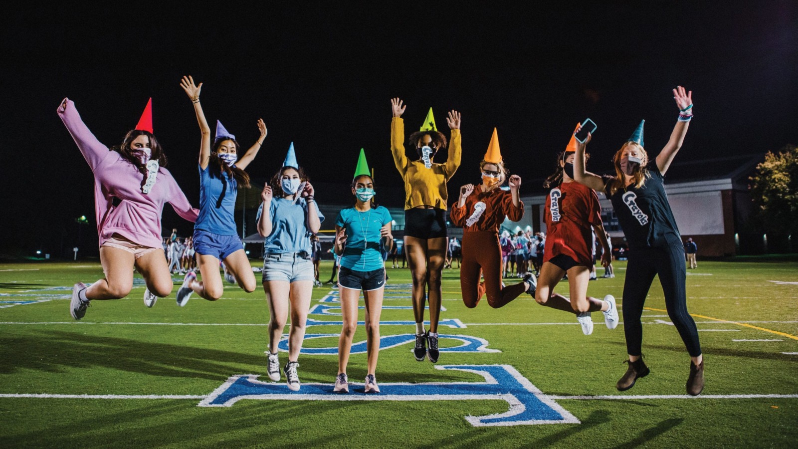 Students dressed as crayons jumping and waving