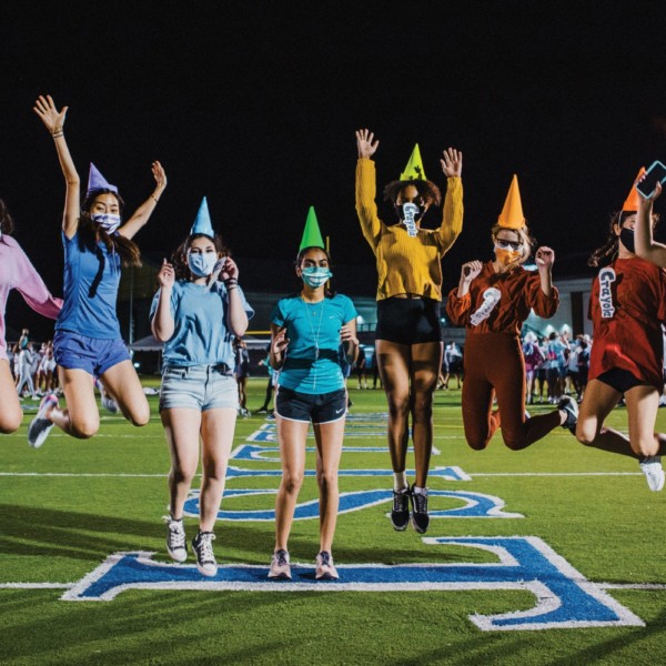 Students dressed as crayons jumping and waving