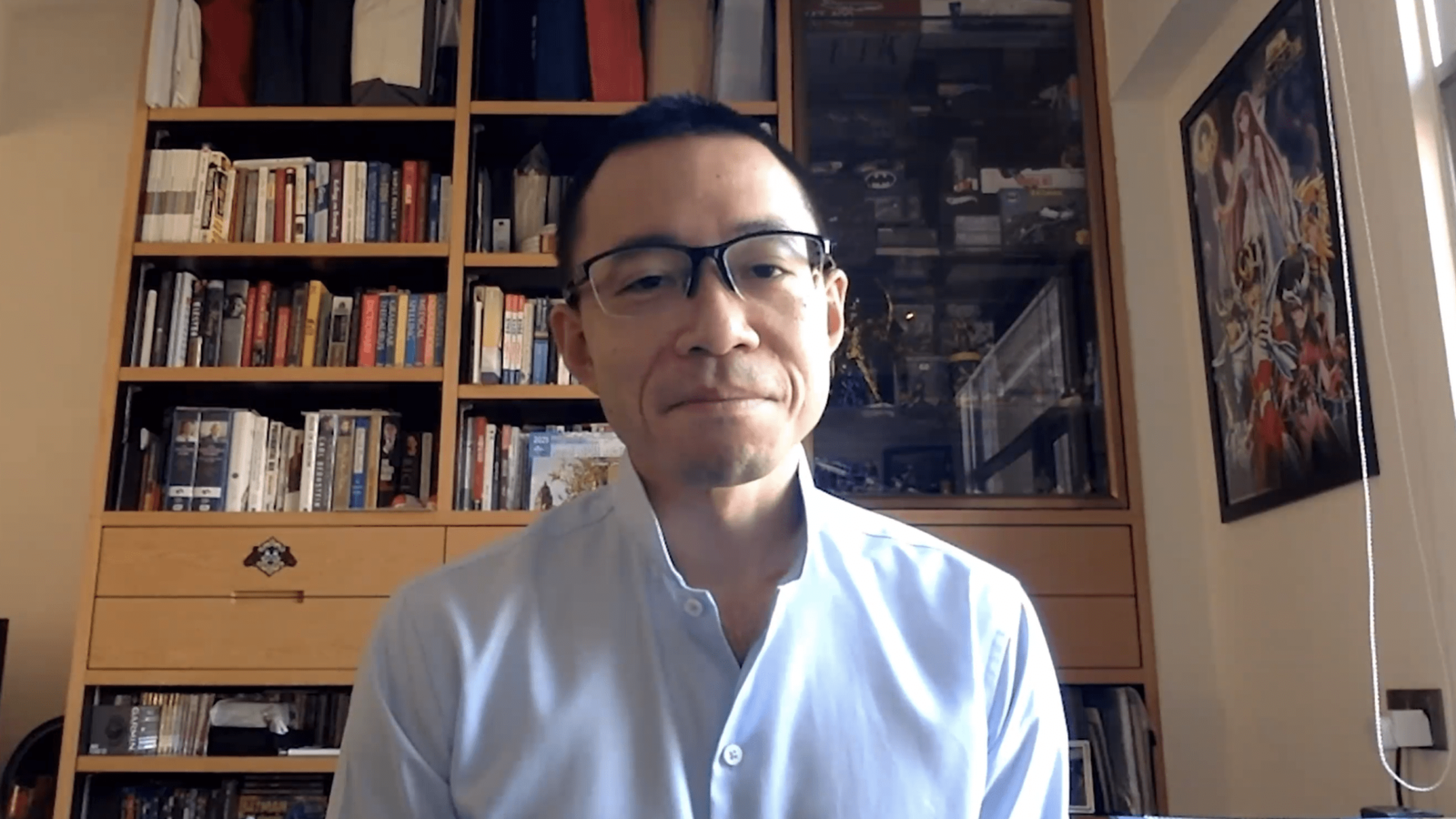 Man in glasses speaking in front of a bookcase