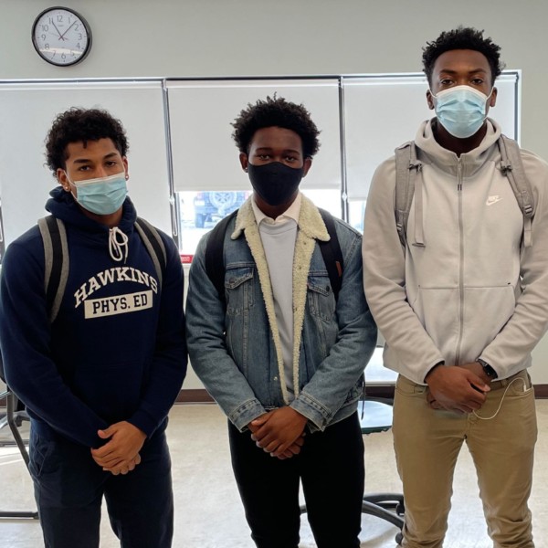 three students and a teacher in a classroom