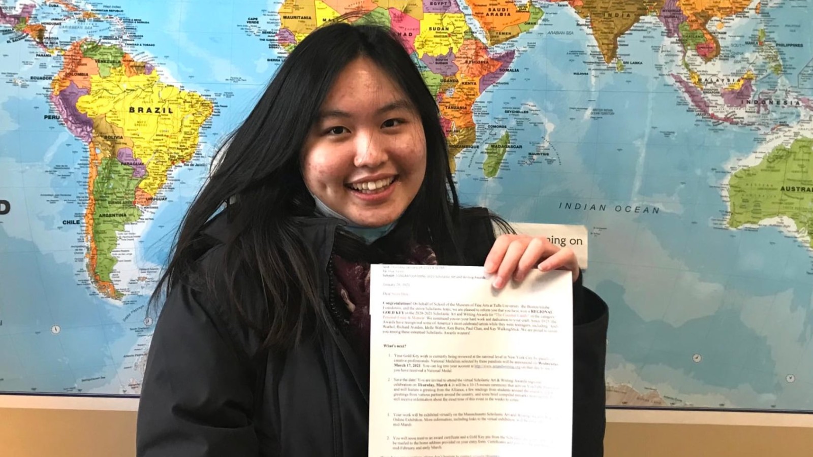 girl holding paper in front of map