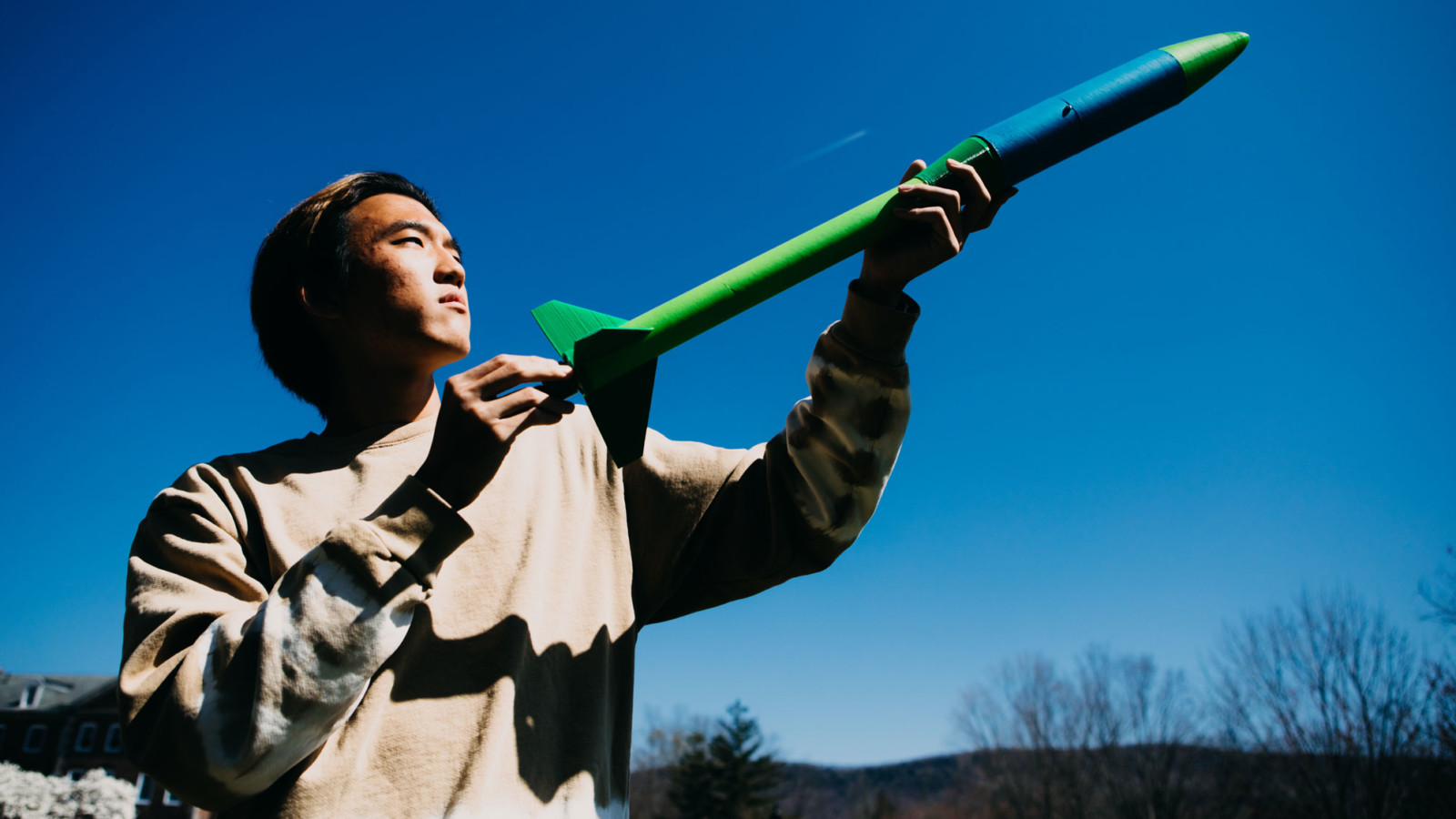 boy with rocket against blue sky and trees