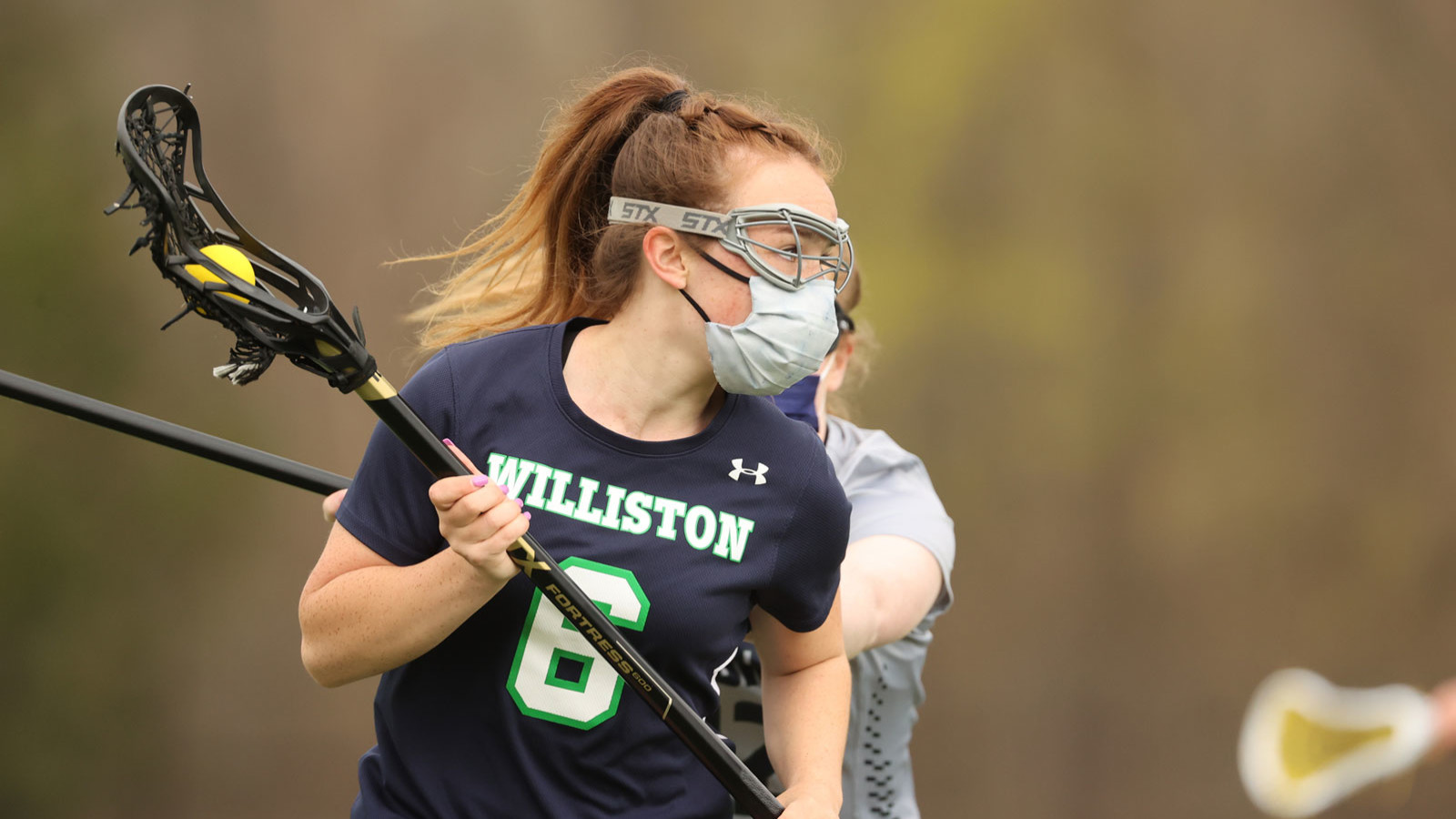 girl wearing mask playing lacrosse