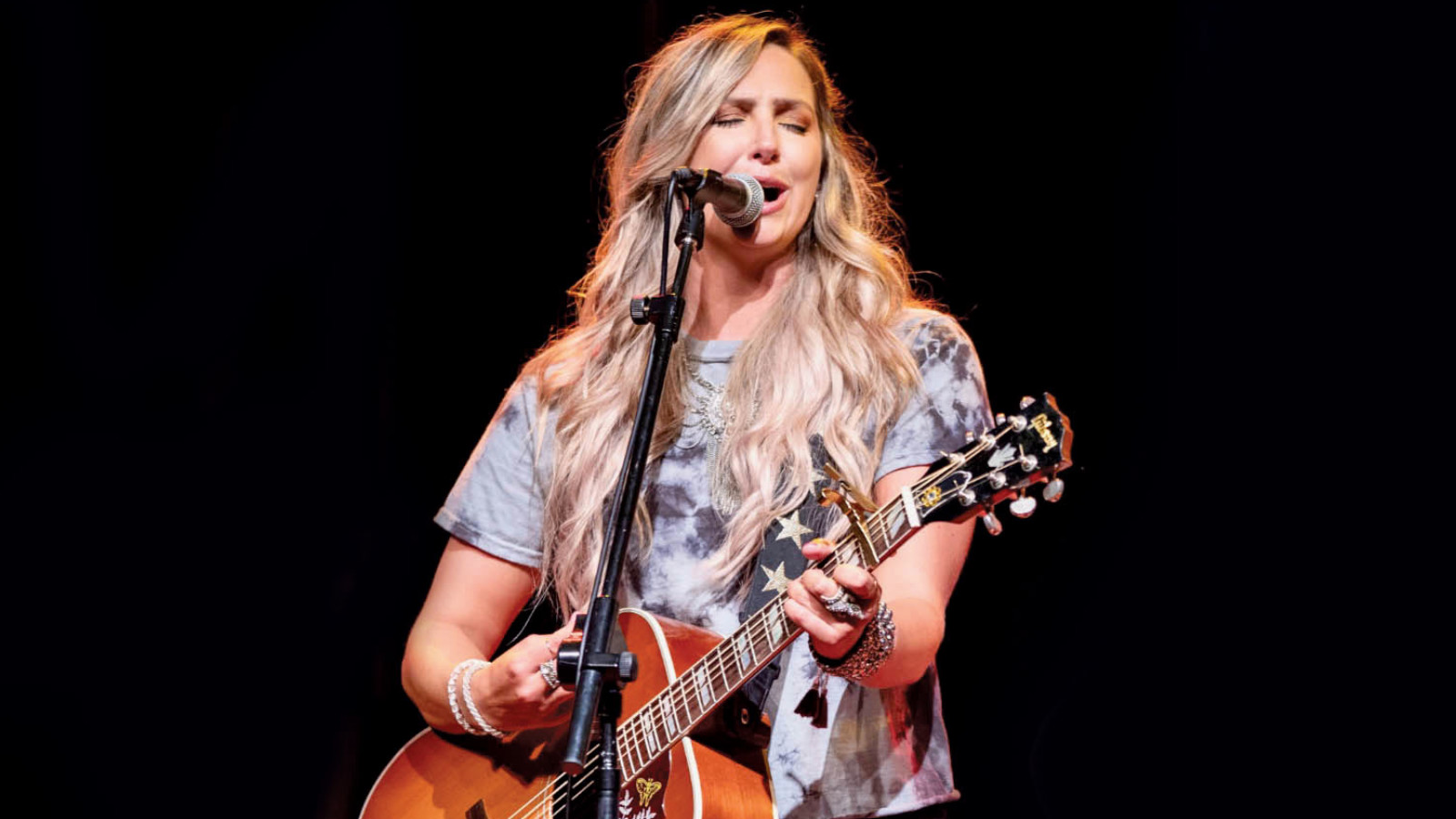 woman with a guitar singing on stage