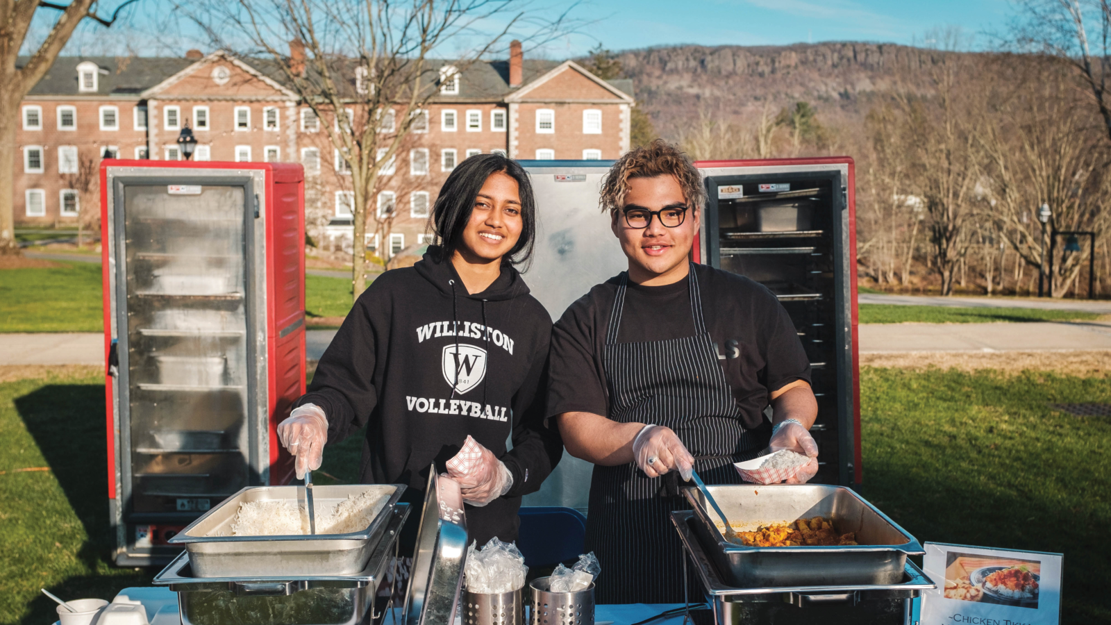 two students outside with trays of food