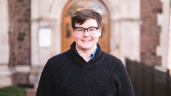 man smiling in front of a stone building