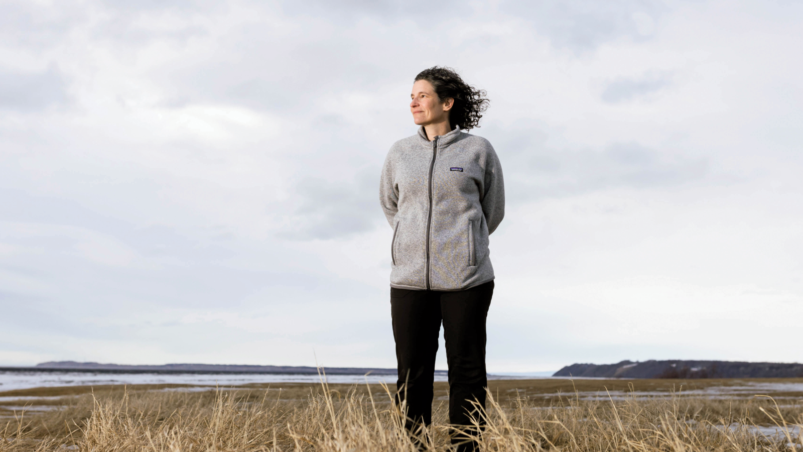 woman in Alaska field with water in background