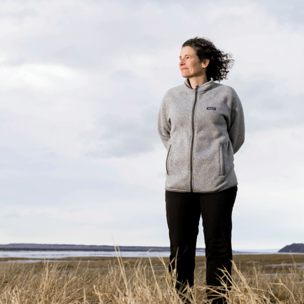 woman in Alaska field with water in background