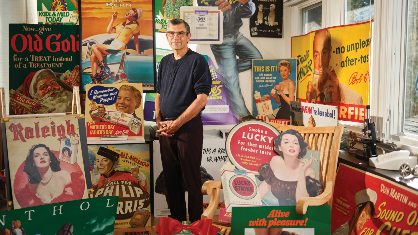 man stands among vintage cigarette ad materials