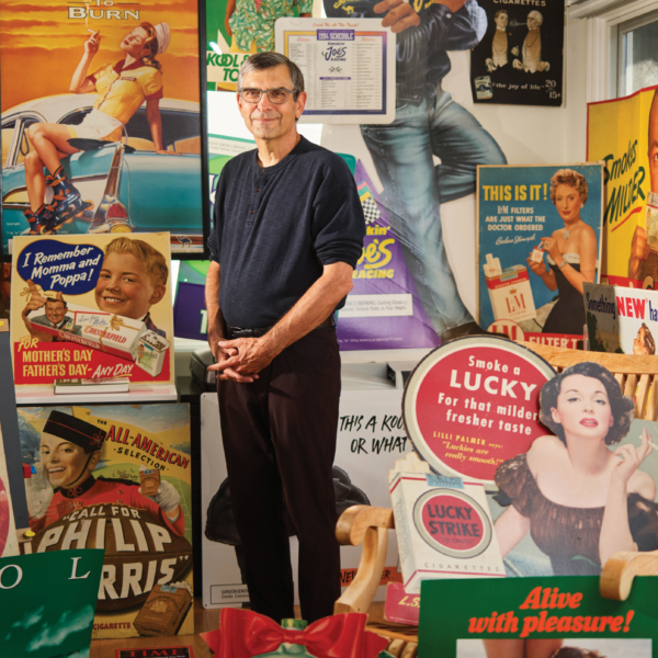 man stands among vintage cigarette ad materials
