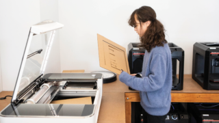 girls using a laser cutter to shape cardboard