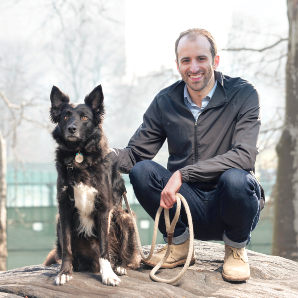 man crouches in Central Park with dog
