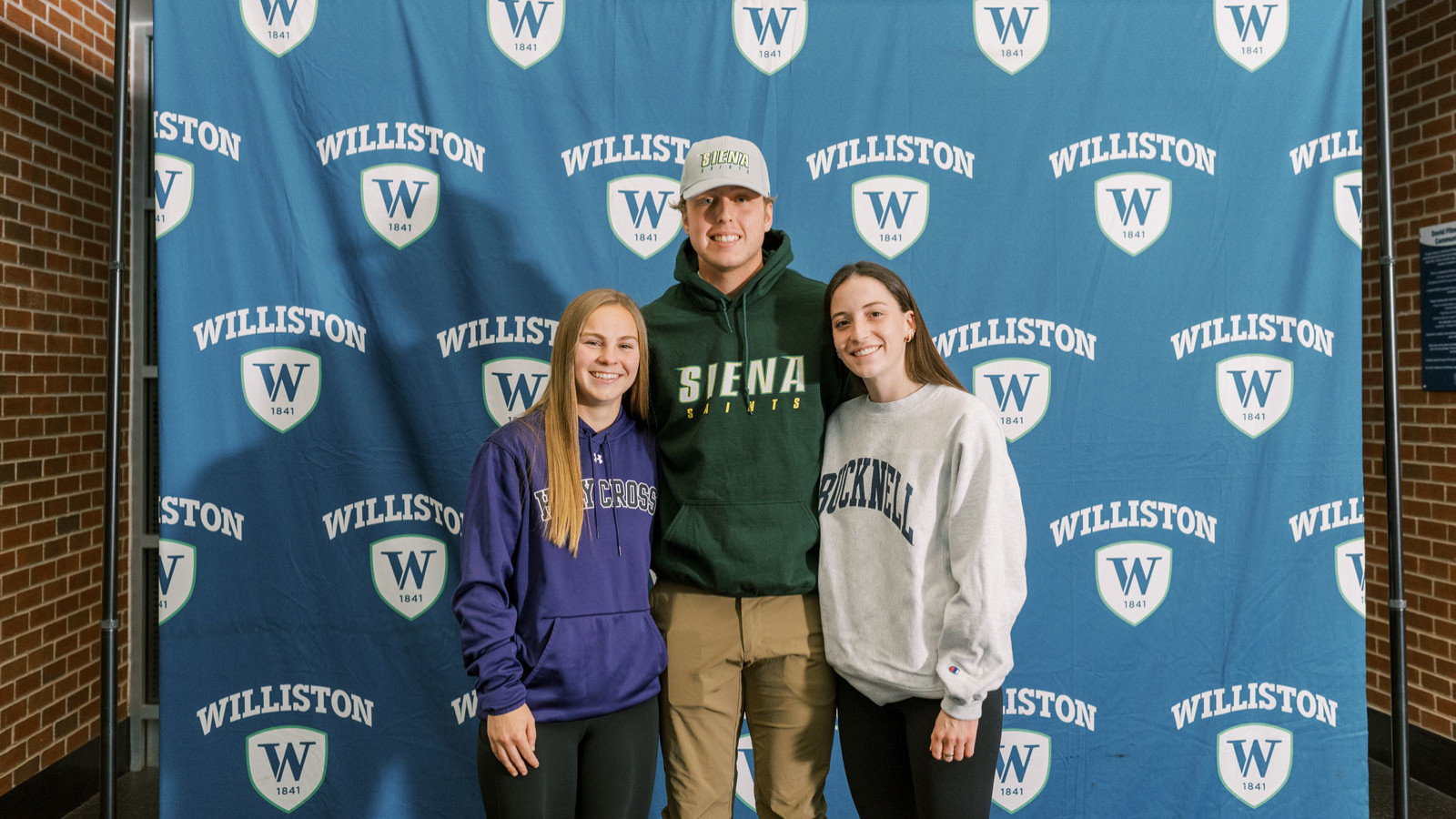 three students in front of banner