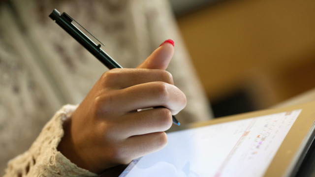 Student holding stylus and computer tablet