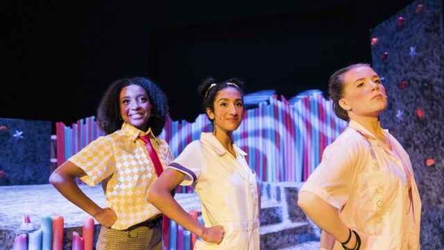 three students posing on stage