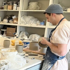 340172015_615329696766168_4318470699354313938_n student works on ceramics piece as students observe
