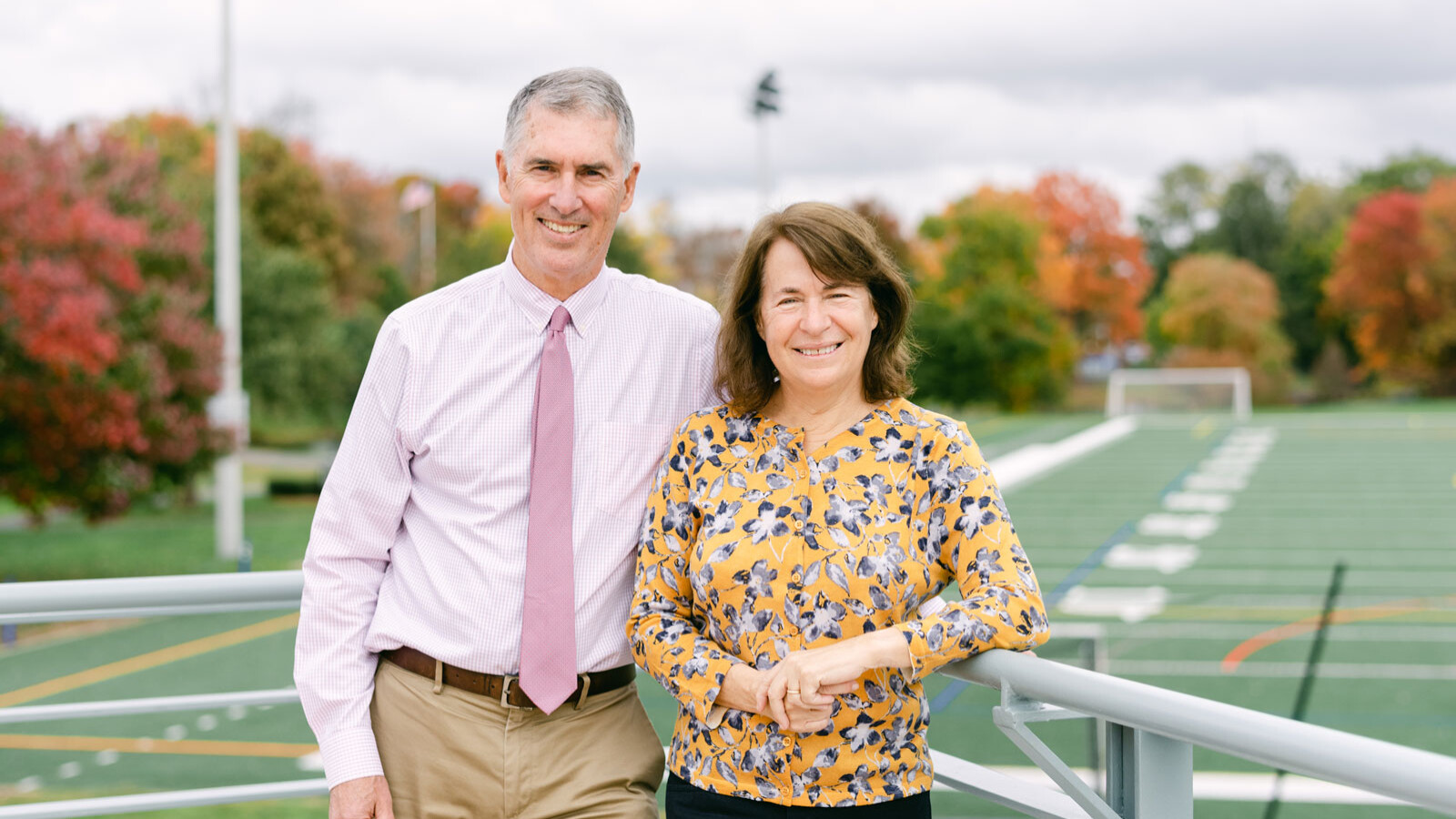 man and woman standing in front of football field