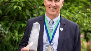 man posing on lawn with trophy