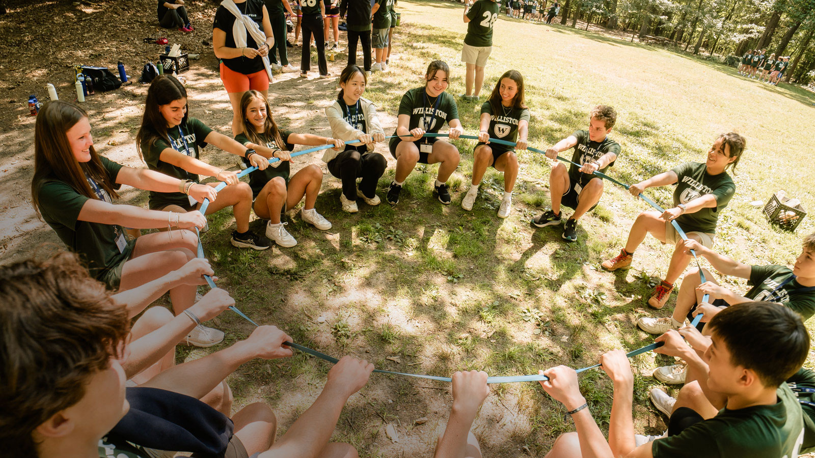 students in green t-shirts in a circle on grass