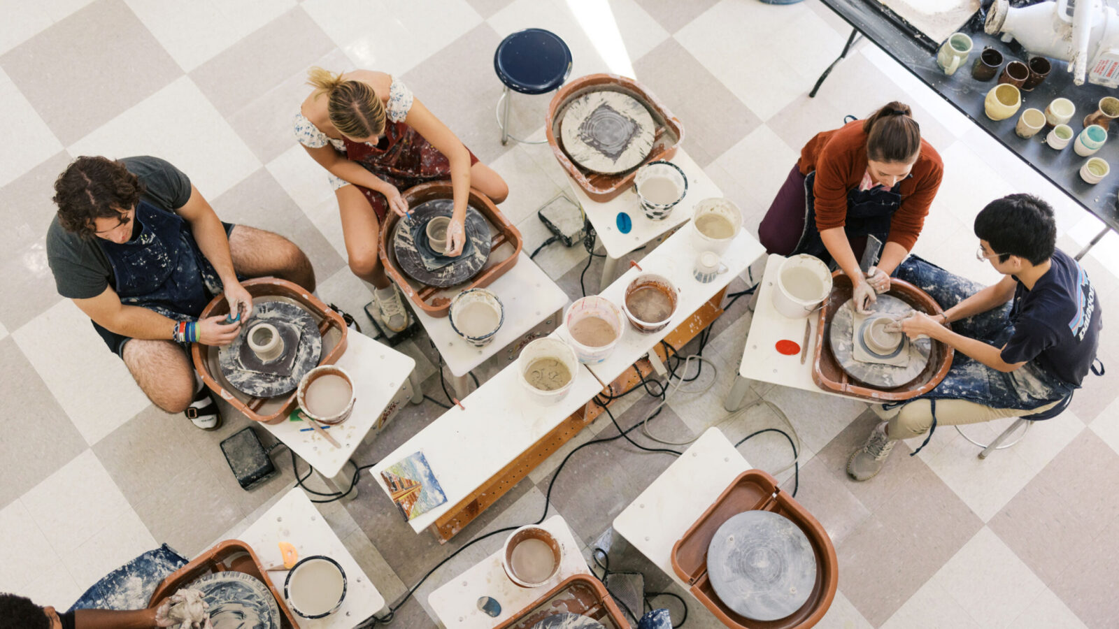students and a teacher using pottery wheels, photo from above