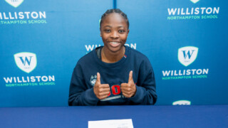 Student giving two thumbs up on school backdrop