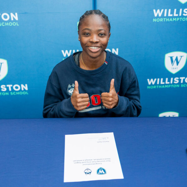 Student giving two thumbs up on school backdrop