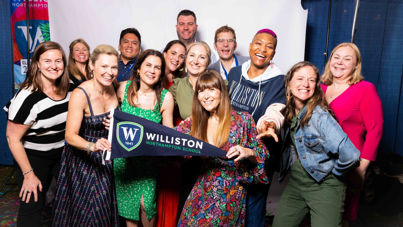 group of people smiling and holding pennant