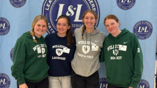 Four female students posing on backdrop in sweatshirts