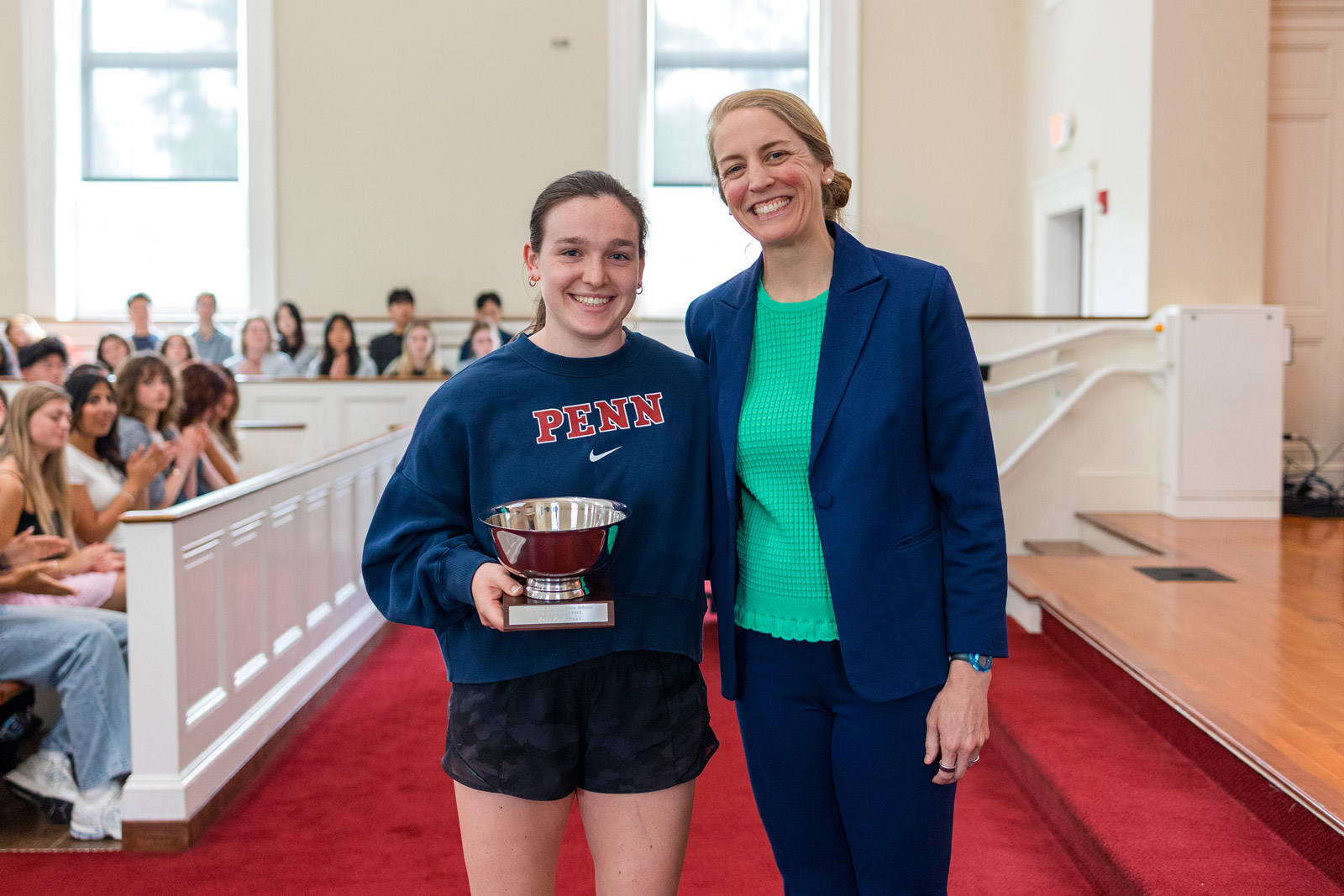 Female student and Athletic Director pose with a trophy
