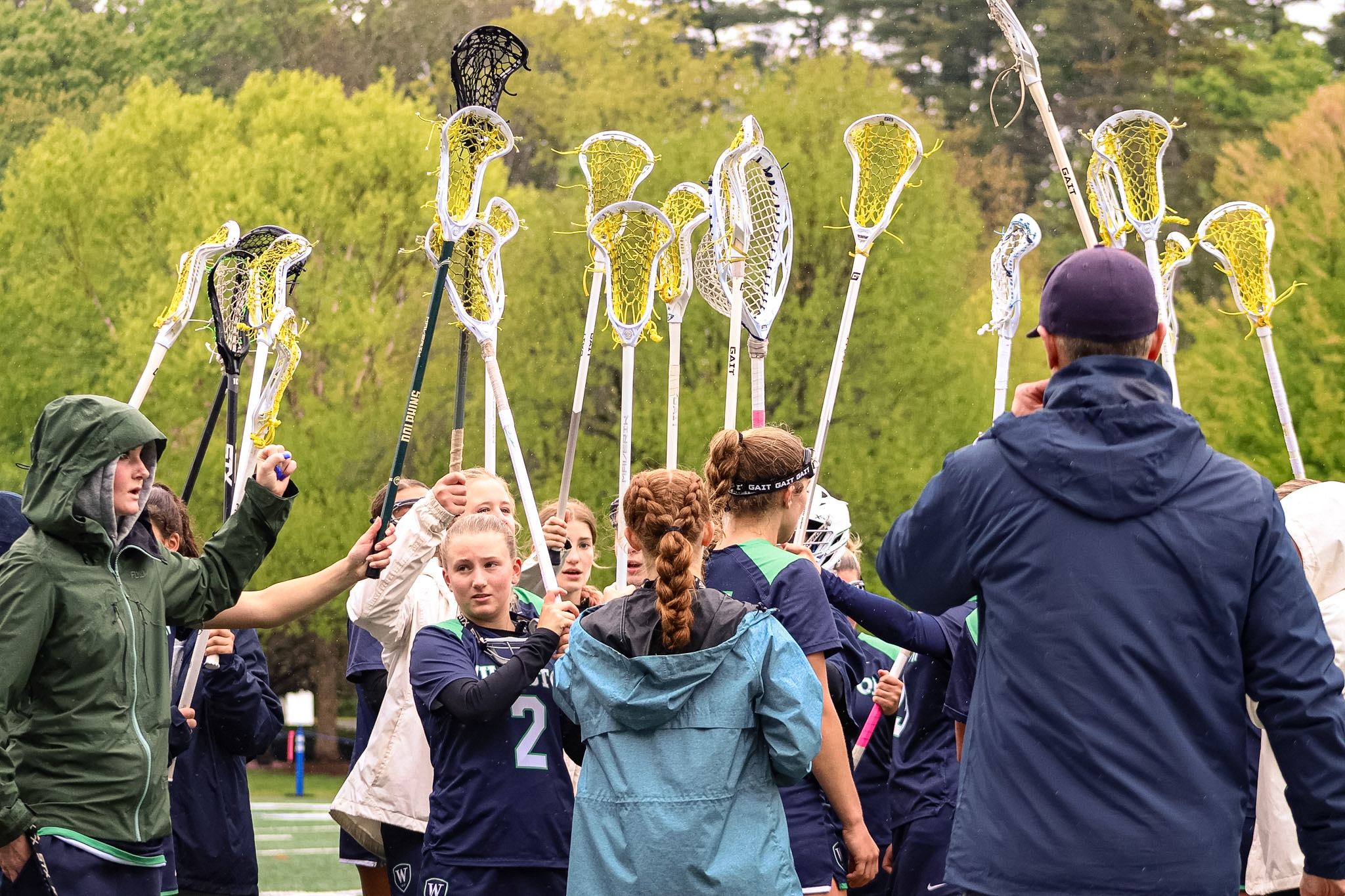 Girls lacrosse players hold up their sticks during a game