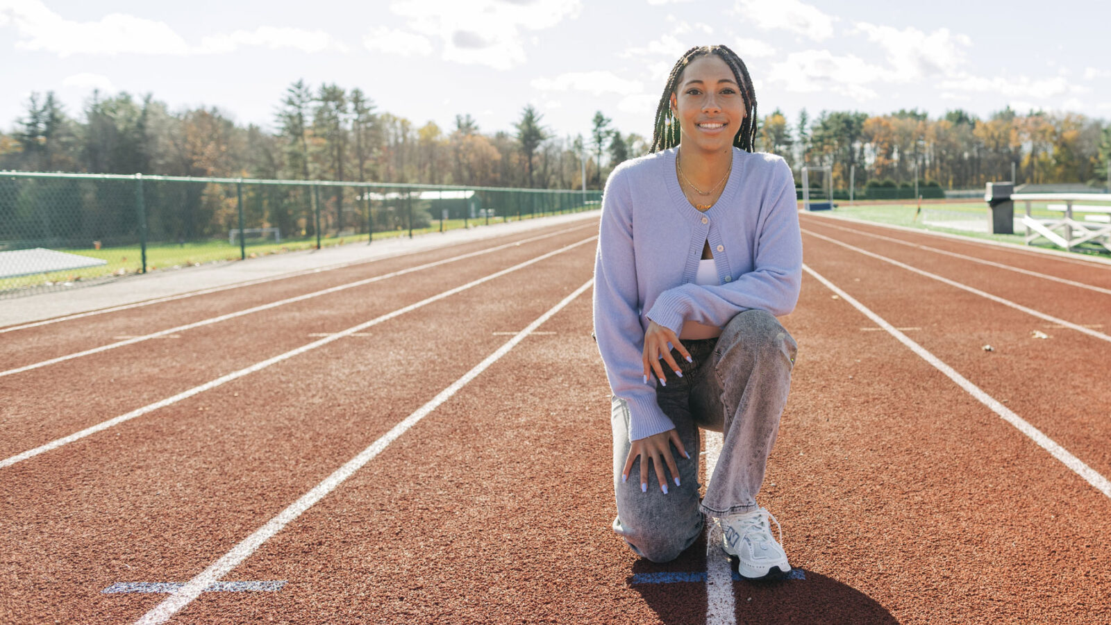 Female student athlete kneeling on track