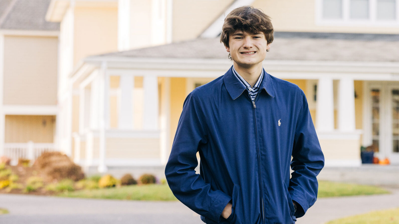 Male student in blue jacket in front of dorm