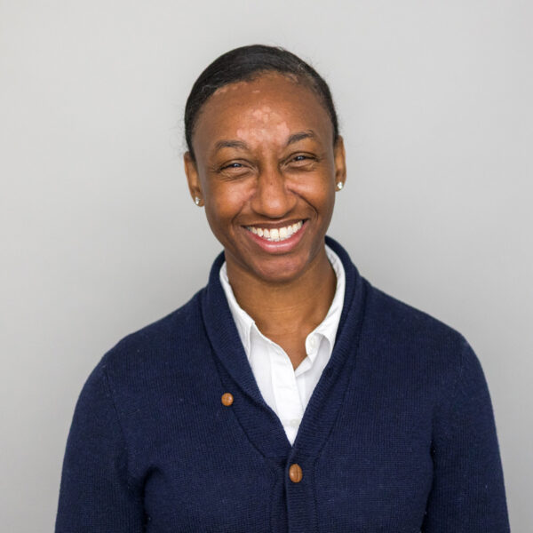 Woman in blue sweater smiling on gray background