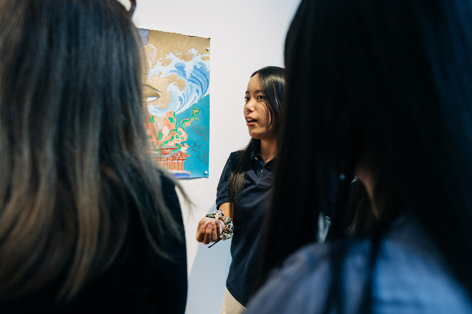 A female students stands in front of a painting she made