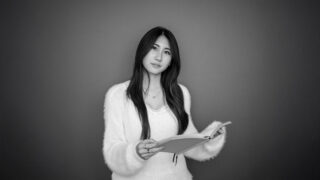 black and white photo of student holding notebook, looking at the camera