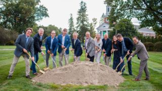 Eleven people pose for picture in front of dirt mound