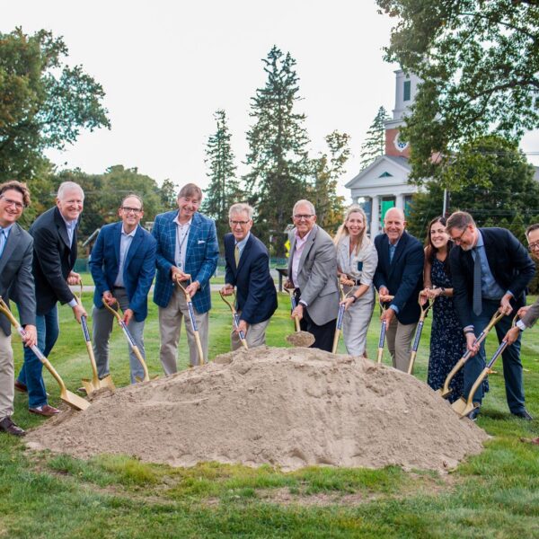 Eleven people pose for picture in front of dirt mound