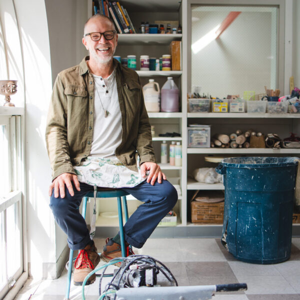 Man sits on stool in art studio